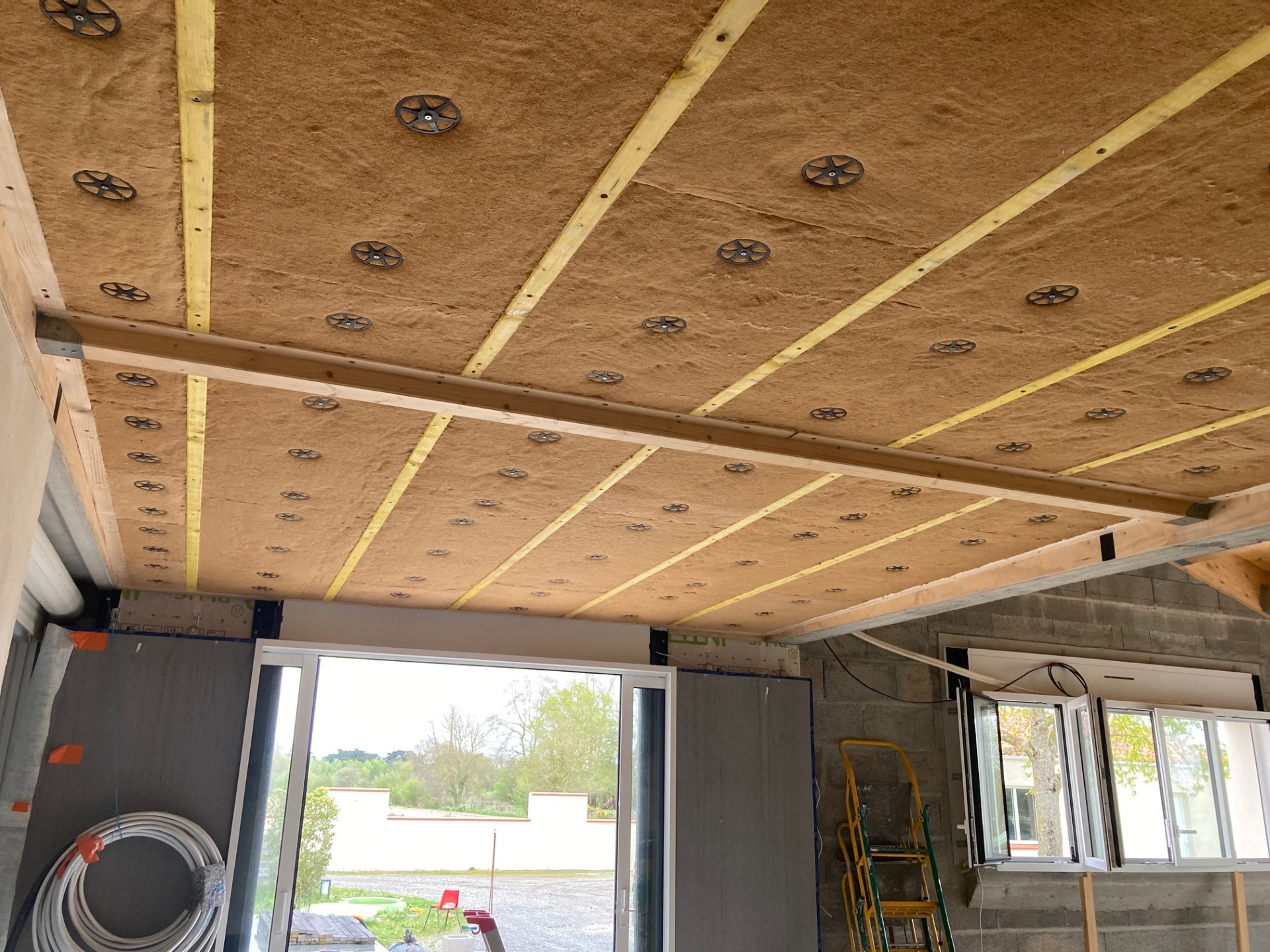 Isolation intérieure en cours de pose sous plafond avec menuiseries ouvertes.